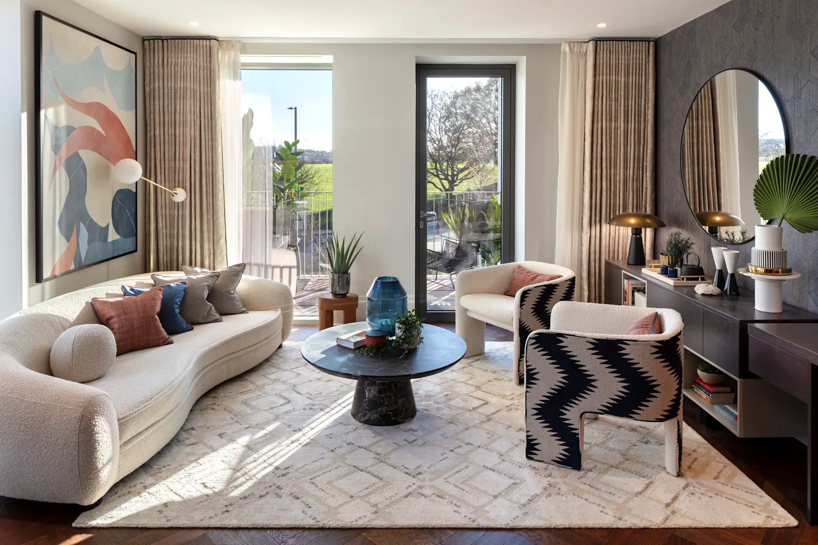 A living room at The Maple, with a white sofa, a coffee table and a large painting on the wall